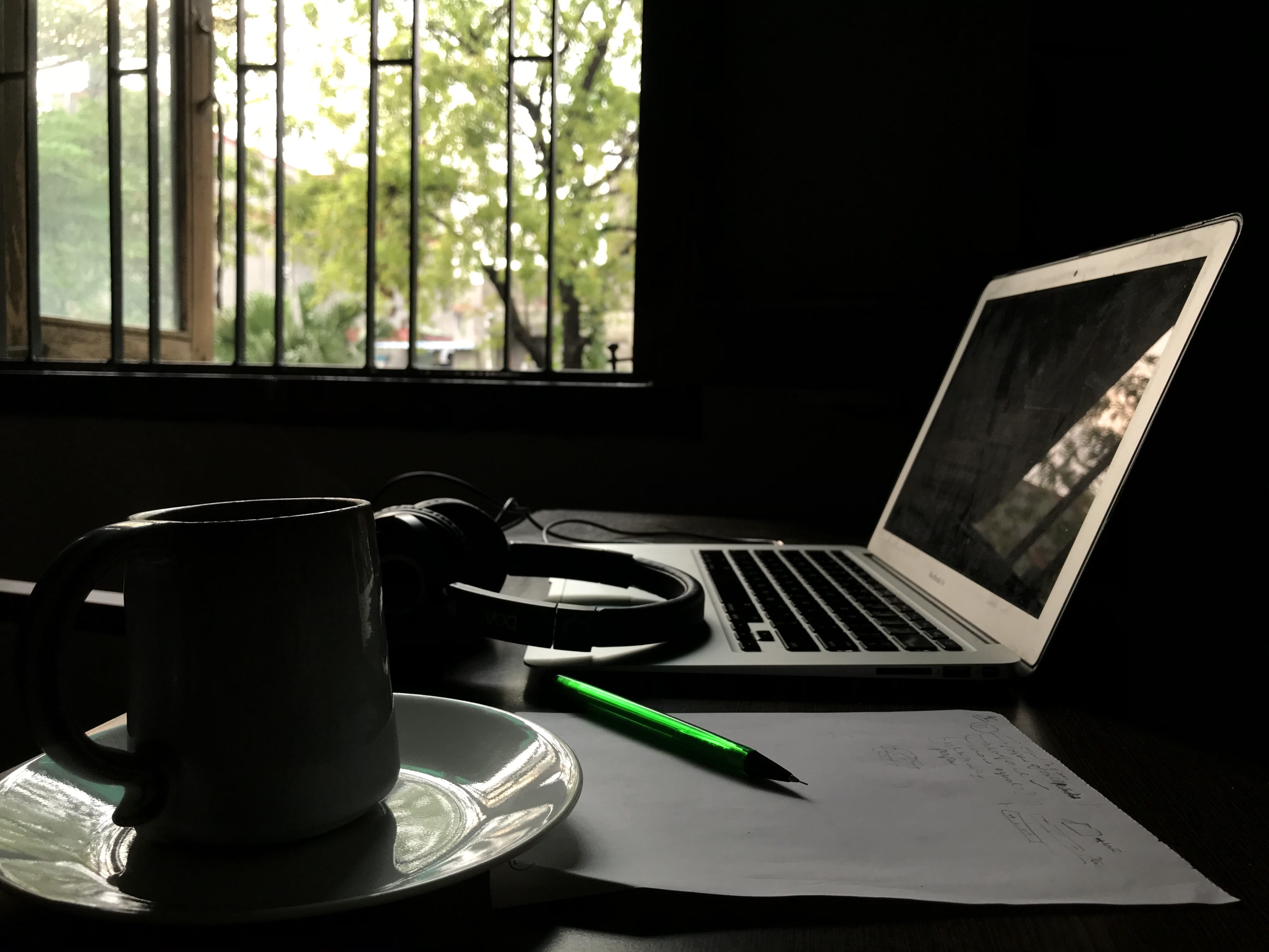Photograph of a laptop, pair of headphones, and a pencil on a piece of paper; Labelled 'Ideas'